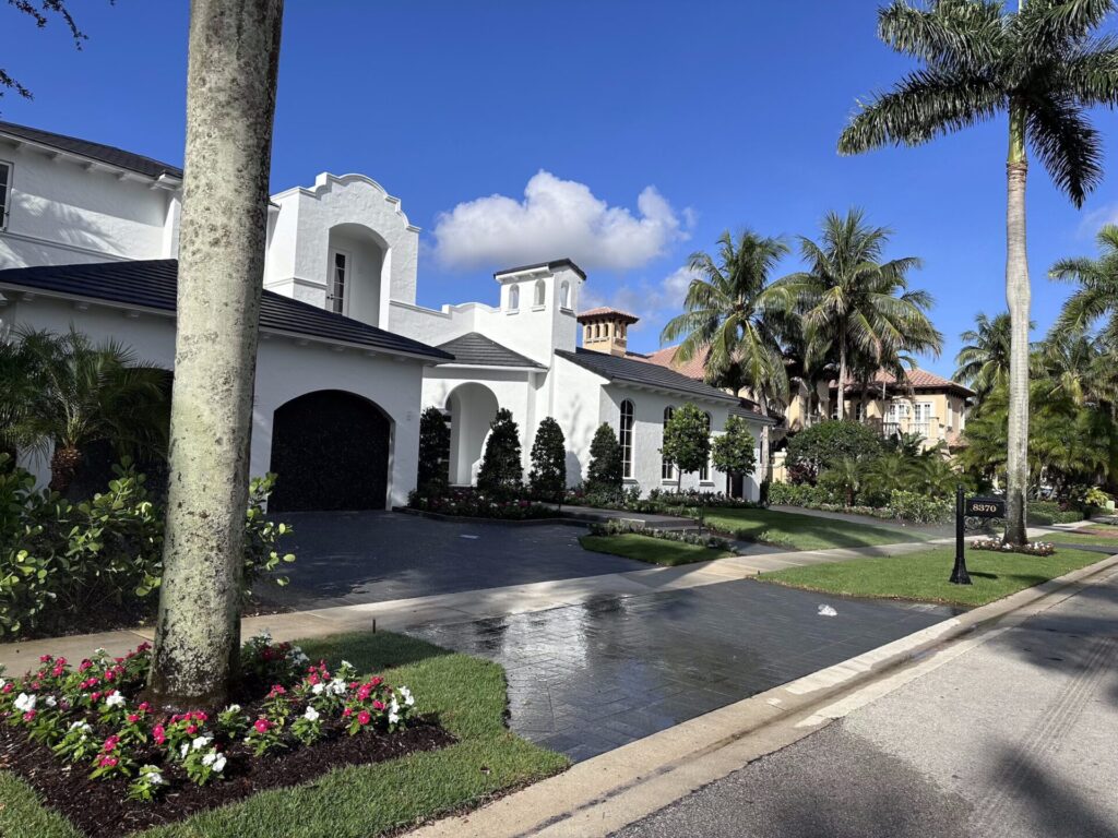 Well-maintained residential property in Boynton Beach featuring manicured landscaping, mature palm trees, and a modern white house, enhancing curb appeal and property value.